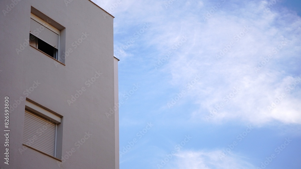 Fototapeta premium simple building facade with windows against cloudy sky