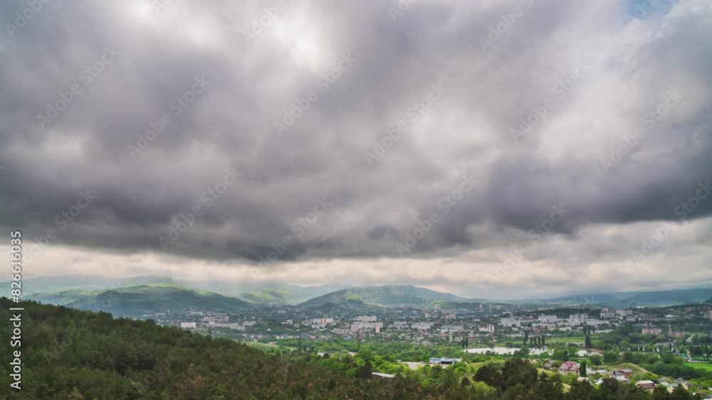 Dark dramatic sky with heavy rain over green hills, provincial town and forest Dark dramatic sky with heavy rain over green hills, provincial town and forest