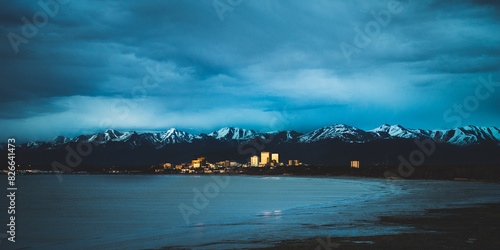 Wide shot of a golden city at dusk  by the ocean with mountains surrounding behind, anchorage alaska
