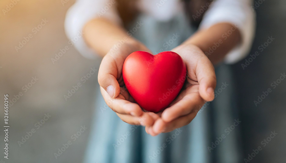 little girl's hand gently holds a bright red heart against a clean, empty, blurred wall background, symbolizing innocence, love, care, and hope in a pure and simplistic manner little girl's hand gently holds a bright red heart against a clean, empty, blurred wall background, symbolizing innocence, love, care, and hope in a pure and simplistic manner
