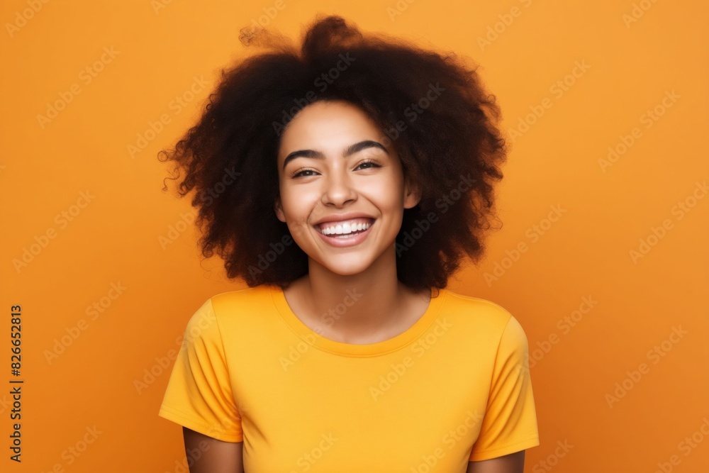 A smiling woman with afro hair on an orange background. A smiling woman with afro hair on an orange background.