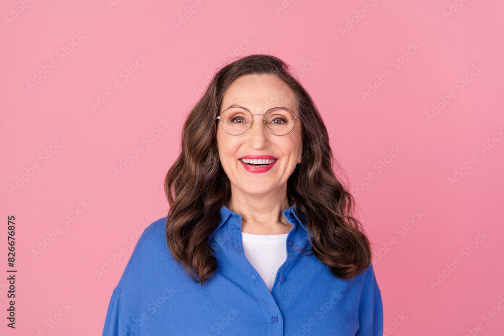 Photo portrait of attractive retired woman cheerful look camera dressed stylish blue clothes isolated on pink color background Photo portrait of attractive retired woman cheerful look camera dressed stylish blue clothes isolated on pink color background