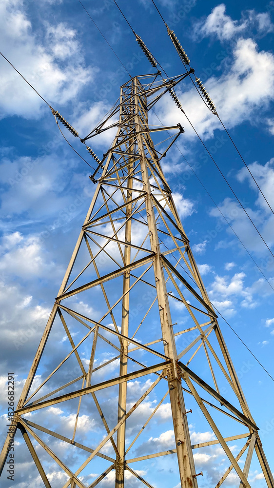 Electric Power Lines and Tower Against Blue Sky and Clouds Electric Power Lines and Tower Against Blue Sky and Clouds