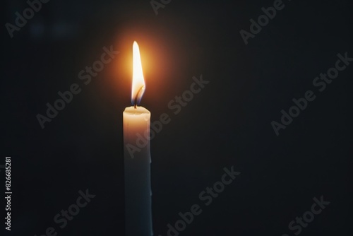 A candle is lit in a dark room. The candle is the only source of light in the room