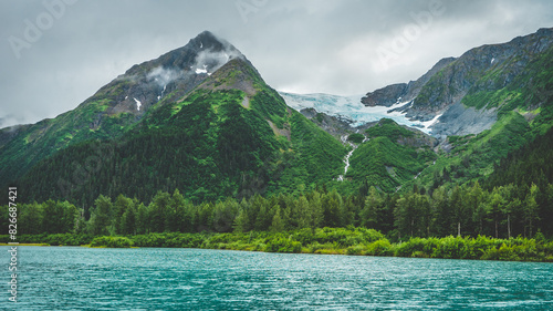 Summer glacier in the mountains with lush greenery in alaska with river and forest below