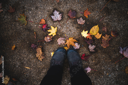Looking down at shoes feet on the road with colorful fall autumn leaves 