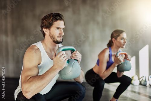 Fitness, squat and couple in gym with kettlebell, power training and workout challenge together at sports club. Man, woman or personal trainer with muscle development, healthy body and exercise. © peopleimages.com