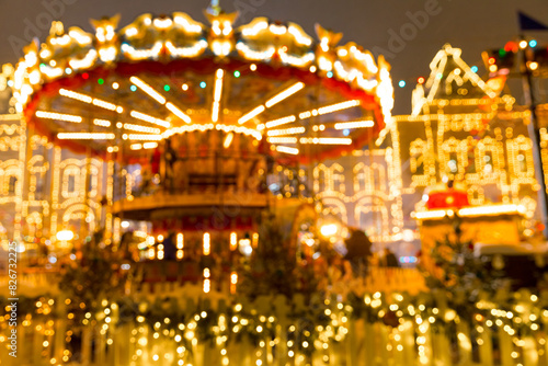 Defocused colorful merry-go-round on Christmas Fair in winter with lots of lights and bokeh on snowy evening © kapichka