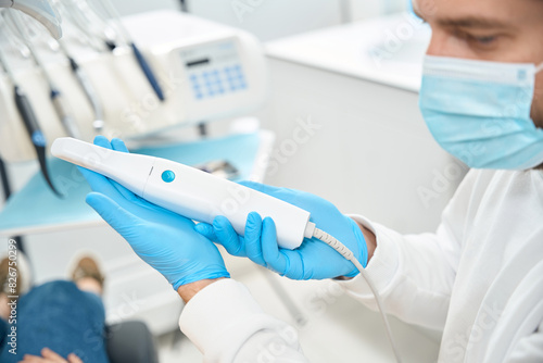 General dentist holding in hands and showing the portable dental scanner photo