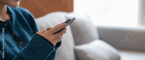 Close up of a woman using mobile smart phone on sofa at cozy home © Waqas