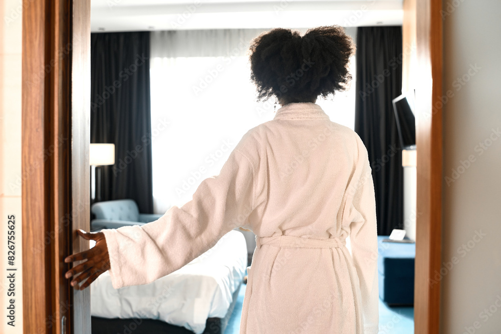 Back view of African American woman wearing bathrobe entering hotel room at resort, copy space Back view of African American woman wearing bathrobe entering hotel room at resort, copy space