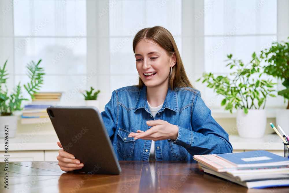 Teenage female student at home looking talking in web camera of digital tablet Teenage female student at home looking talking in web camera of digital tablet
