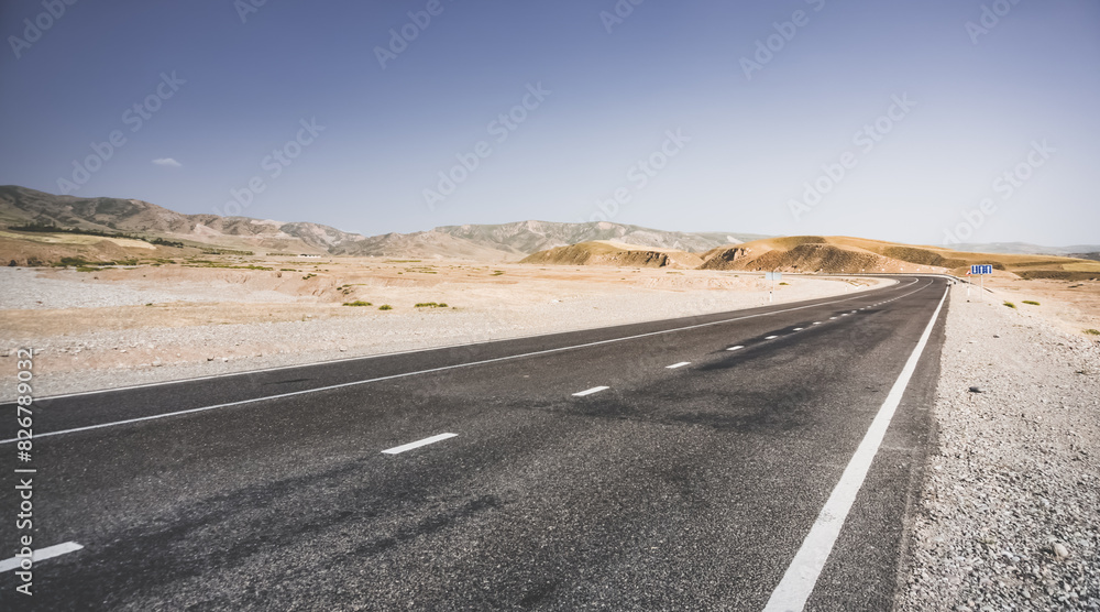 Asphalt road among hills and fields in the mountains of Tajikistan, a beautiful road in nature, panoramic landscape on a summer day Asphalt road among hills and fields in the mountains of Tajikistan, a beautiful road in nature, panoramic landscape on a summer day