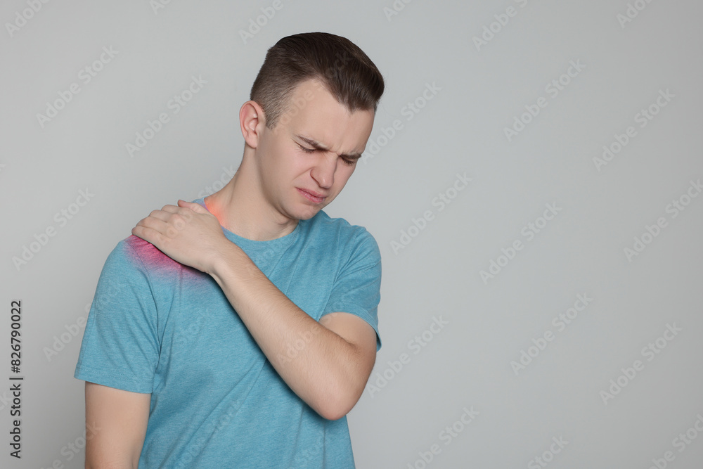 Man suffering from pain in shoulder on grey background. Space for text Man suffering from pain in shoulder on grey background. Space for text