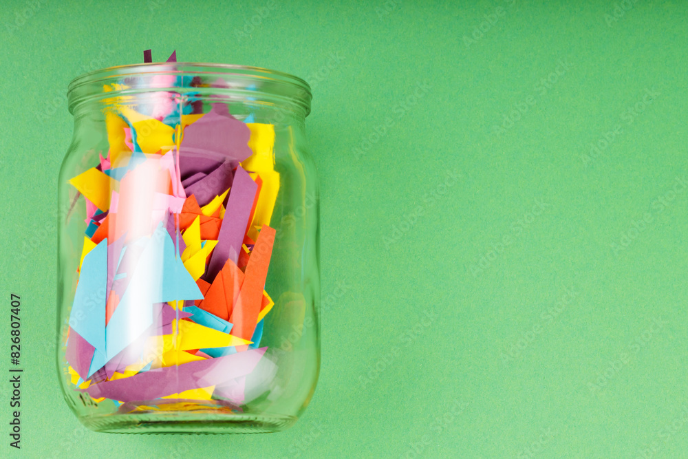 Obraz premium Glass Jar Filled with Colorful Paper Scraps, Reducing Paper Waste Concept, Copy Space