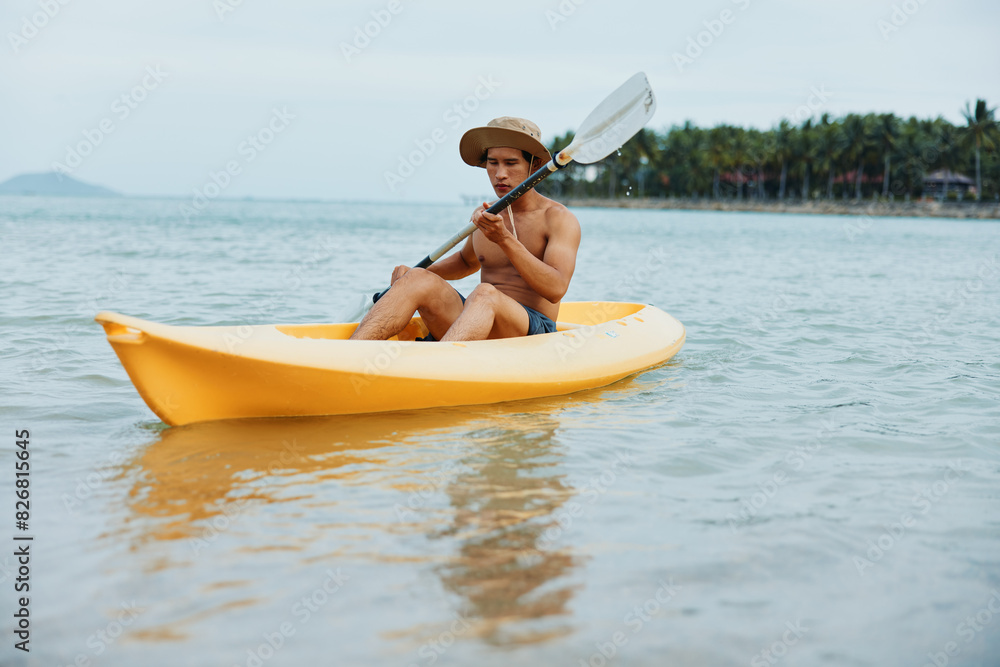 Happy Asian man kayaking on a tropical beach vacation: Adventures in the Sun