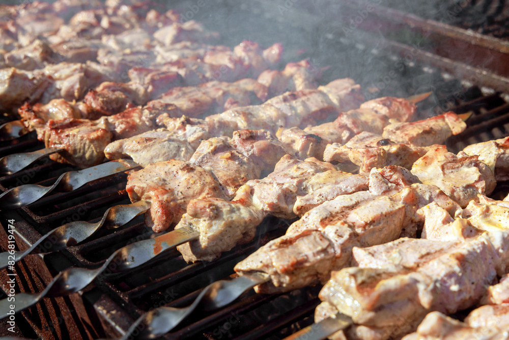 An outdoor barbecue grill is used to grill pork skewers over charcoal An outdoor barbecue grill is used to grill pork skewers over charcoal