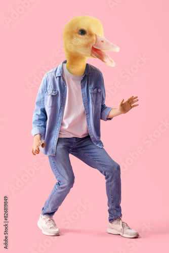 Young man in headphones with mobile phone dancing on pink background photo