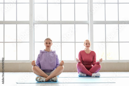 Sporty young women meditating in gym