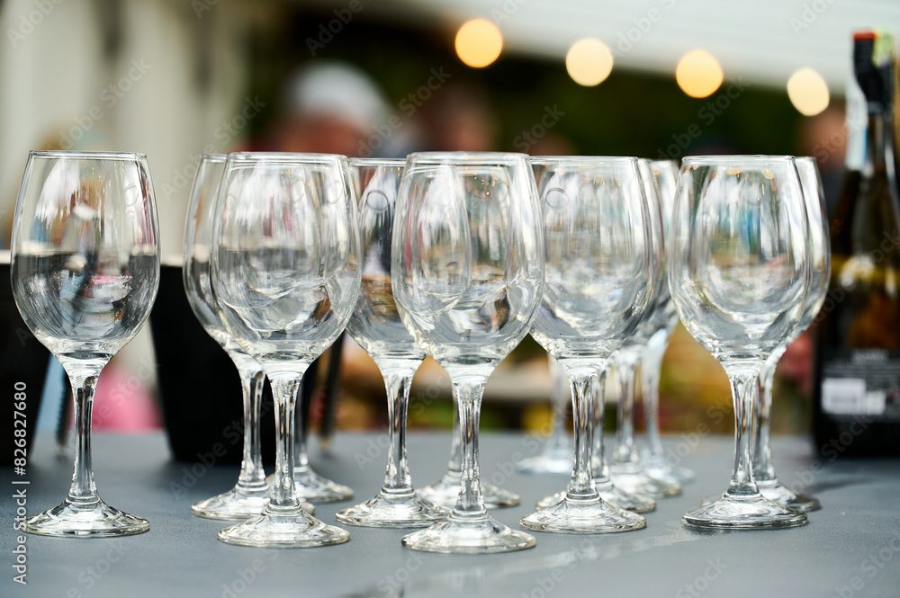 empty wine glasses stand in a row on the table. blurred background. A garland shines in the background empty wine glasses stand in a row on the table. blurred background. A garland shines in the background