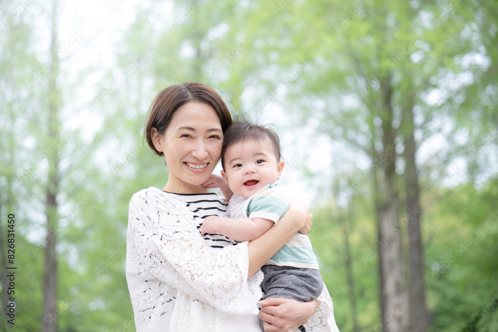 Mother holding her baby in a backlit fresh green park Image of a nice smile of happiness and well-being Looking at the camera Mother holding her baby in a backlit fresh green park Image of a nice smile of happiness and well-being Looking at the camera