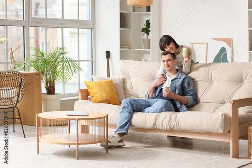 Young couple in love with cups of coffee at home