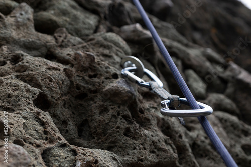 Rock climbing safety equipment, dynamic rope and carabiner fixed on wall photo