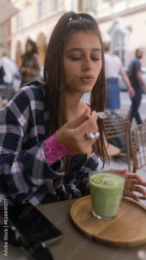 A striking young traveler discusses on her phone while seated at a restaurant terrace in Bologna, Italy. A striking young traveler discusses on her phone while seated at a restaurant terrace in Bologna, Italy.
