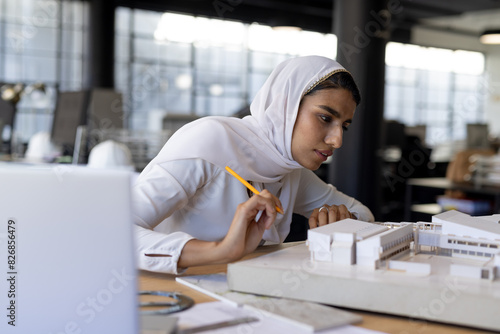 In a modern office, Indian woman in white hijab works on architectural model photo