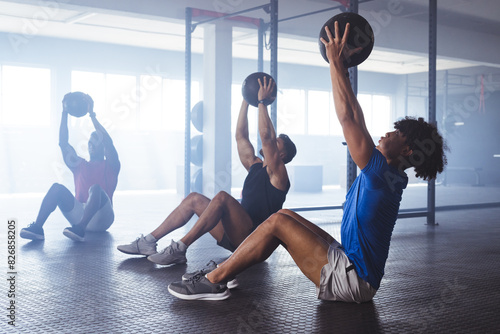 Three young, fit, diverse men working out with medicine balls at gym photo