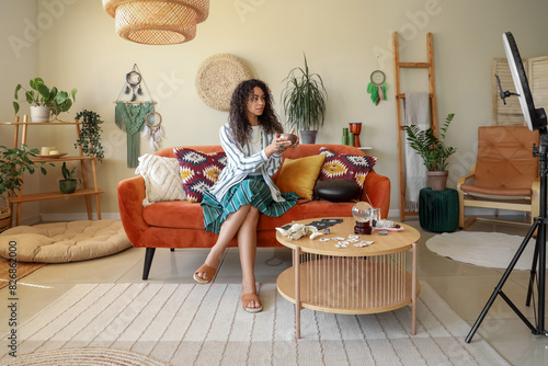 Young African-American witch with Tibetan singing bowl recording video at home photo