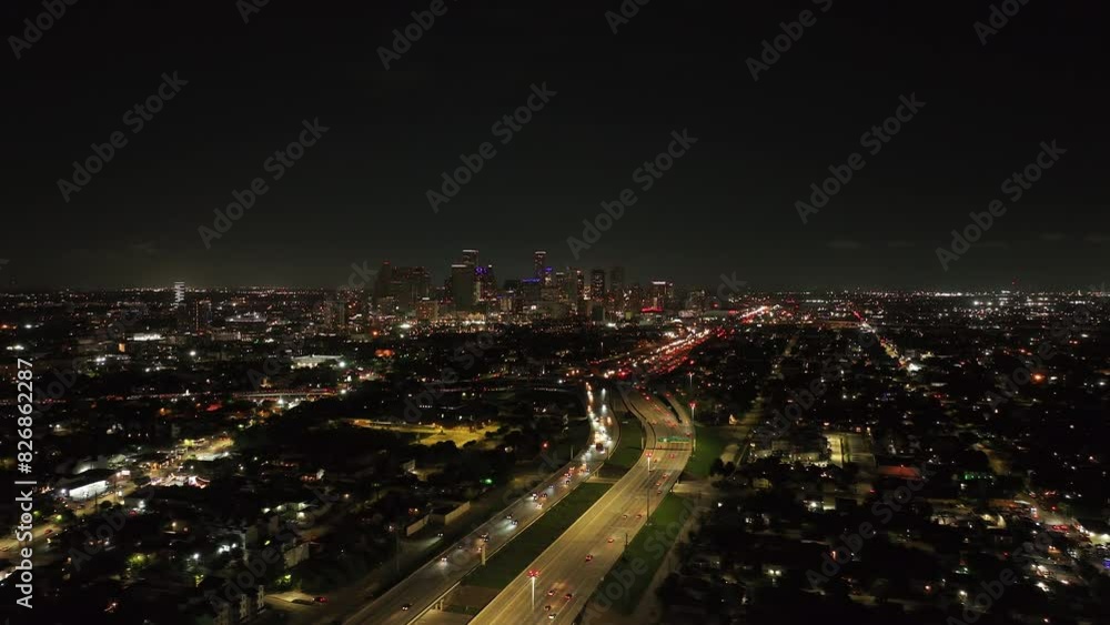 Bustling streets in the vibrant nighttime cityscape of Houston, Texas, with illuminated buildings and heavy traffic in the highway