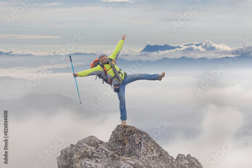 Hiker with backpack cheering elated and blissful with arms raised on top mountain foggy after hiking. Hiker men's hiking living healthy active photo