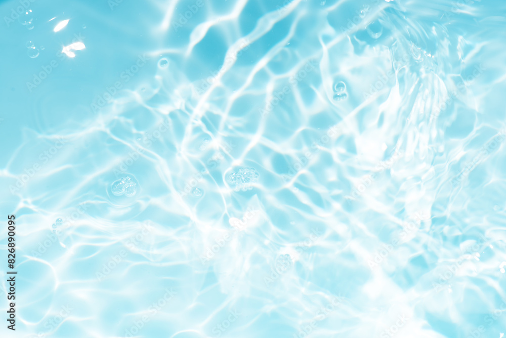 Obraz premium Blue water with ripples on the surface. Defocus blurred transparent blue colored clear calm water surface texture with splashes and bubbles. Water waves with shining pattern texture background.
