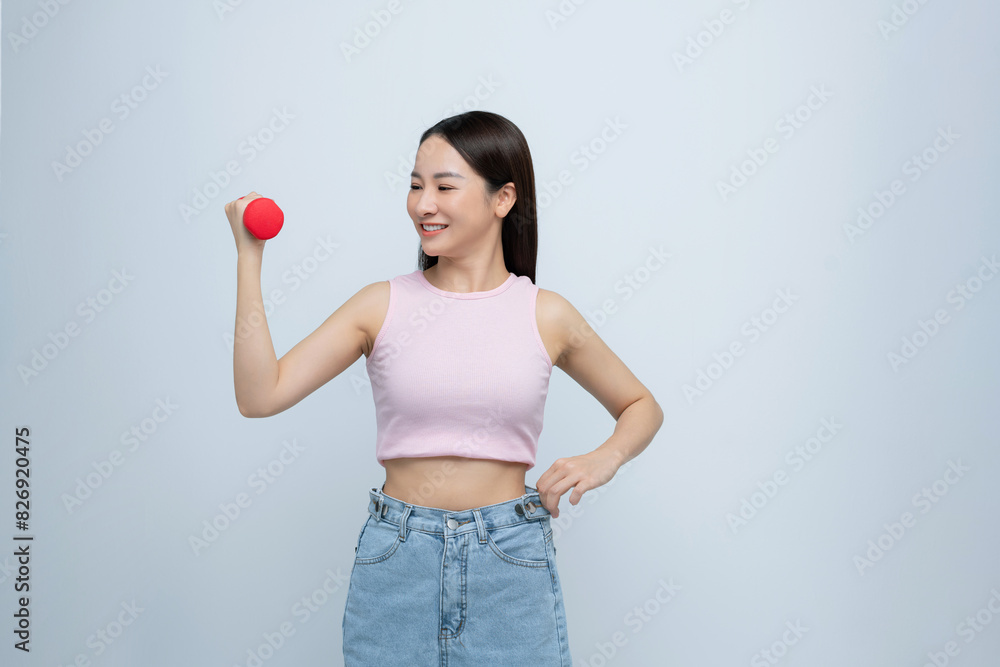 Woman lifting dumbbell in oversized jeans unwearable Woman lifting dumbbell in oversized jeans unwearable