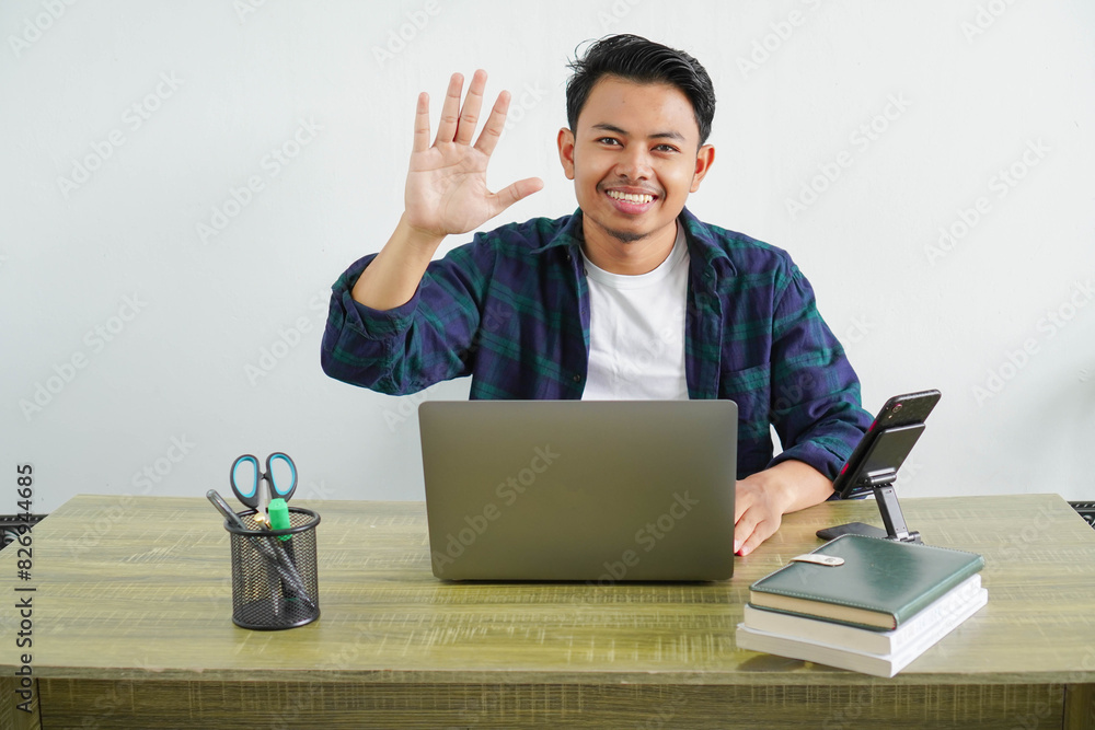 young asian freelancer sitting in workplace saluting with hand with happy expression young asian freelancer sitting in workplace saluting with hand with happy expression
