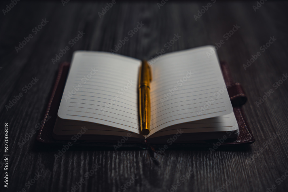 Fototapeta premium A notebook with a gold pen on the table in the candlelight