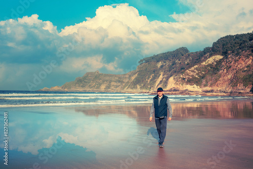 Rocky seascape with cloudy day sky. Atlantic seashore. A man walking on the beach © vvvita
