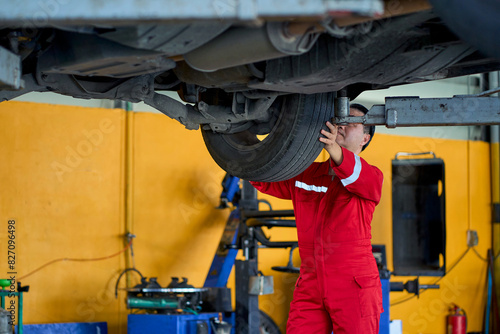 Senior asian technician working with check a car wheel on lifting power machine in car garage