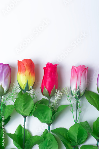 Colorful artificial roses on white background with copy space for text.