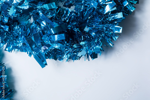 Blue tinsel on a white background with copy space for text. Concept of Christmas and New Year.