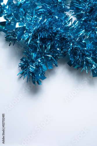 Blue tinsel on a white background with copy space for text. Christmas and New Year concept. Vertical short
