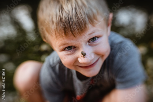 Close up of child smiling with tiny frog on his face photo
