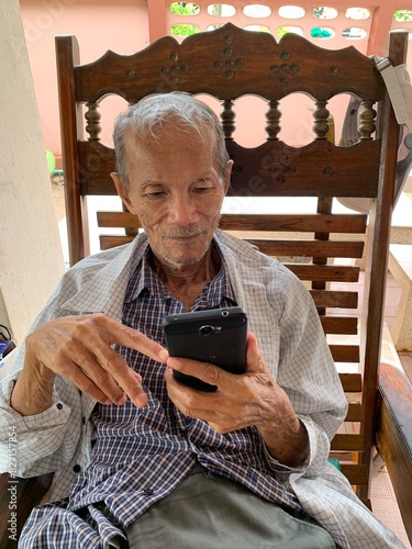 Old man sitting and looking at a mobile phone