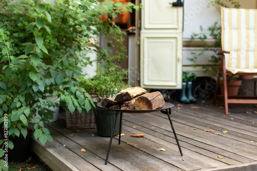 Iron firepit near outside caravan trailer. Metal black fireplace bowl with logs in garden. Backyard with RV house with fire steel pit round fireplace appliance for outdoor party.	 photo