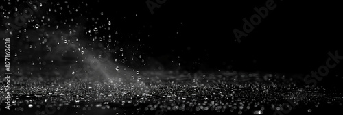 Water spray on black background, white water droplets falling in the air, particles of dust floating in space.Abstract black and white bokeh lights with sparkling particles creating a dramatic