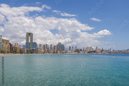 Aerial drone photo of the beautiful town of Benidorm in Spain showing the south beach Promenade golden sandy beach and apartments on a sunny summers day with a blue sky and a few clouds