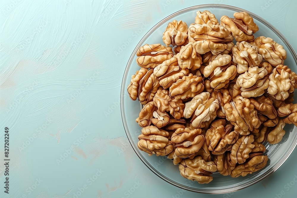 A clear glass plate filled with shelled walnuts on a light blue background, highlighting the texture and natural look of the nuts. A clear glass plate filled with shelled walnuts on a light blue background, highlighting the texture and natural look of the nuts.