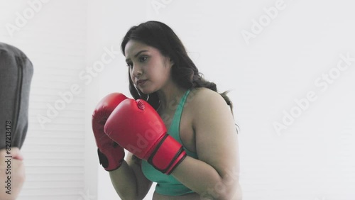 portrait of chubby woman wearing boxing gloves practicing
