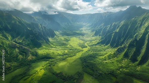 Aerial view of a verdant valley with dramatic cliffs and sunlit meadows under a cloudy sky